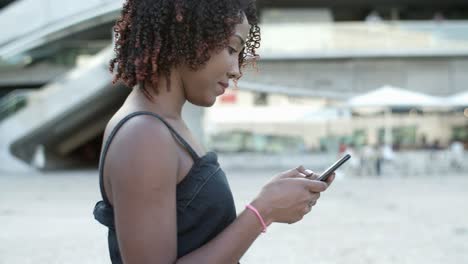 Lächelnde-Afroamerikanische-Lockige-Frau,-Die-Ihr-Telefon-Benutzt